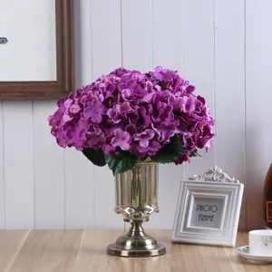 Bouquet di ortensie artificiali viola in grande vaso di vetro per decorazione.
