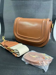 Detailed view of the brown saddle bag showcasing fine stitching and metallic hardware.