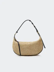 Detailed view of the woven straw shoulder dumpling bag, highlighting texture and black leather strap.