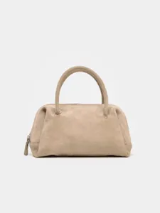 Gros plan détaillé sur le sac bowling minimaliste en suède avec une texture douce et élégante.