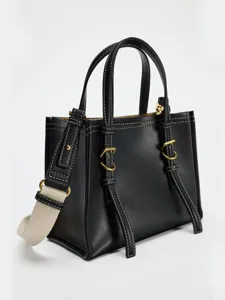 Vue detaillee d'un sac a main chic en cuir noir avec des coutures et accessoires.