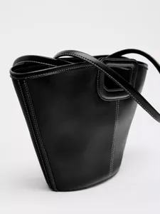 Detailansicht der schwarzen Ledertasche mit weißer Kontrastnaht und praktischen Tragegriffen.