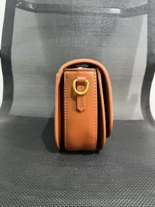 Brown leather saddle bag side detail view showing neat stitching and metal d-ring hardware.
