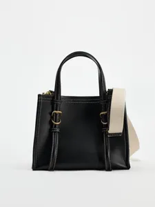 Détail de mini sac à main en cuir noir avec coutures contrastées et large bandoulière.