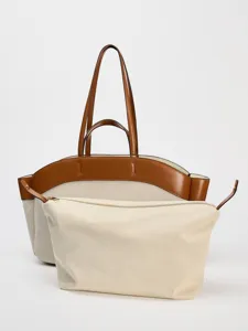 Dettaglio della borsa tote in tela con manici in pelle strutturati e pochette abbinata.