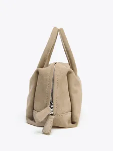 Vue détail d'un sac à main boston en suédine beige avec double poignée et fermeture éclair.