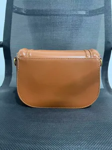 Brown leather saddle bag detail view, showing exquisite stitching and flap closure.