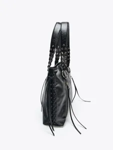 Nahaufnahme der schwarzen Ledertasche mit Nieten, geflochtenen Griffen und Quasten.