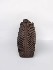 Vista lateral detallada de bolso de cuero tejido marrón oscuro con elegante textura fina.