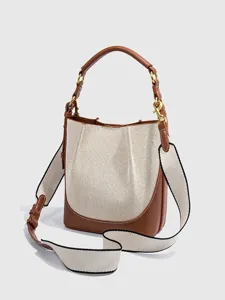 Detailansicht der stylischen Canvas-Beuteltasche mit braunem Lederbesatz und breitem Gurt.
