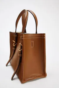 Sac cabas miniature en cuir marron classique avec double poignées et anneaux métalliques.