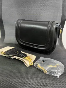 Black leather saddle bag with magnetic flap closure, contrast stitching, and adjustable straps.