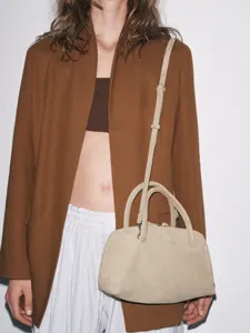 Détail de sac bowling en suède beige, doté de deux anses et d'une bandoulière.