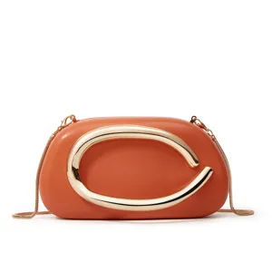 Detail view of mini orange leather crossbody bag with striking gold C metal clasp hardware.