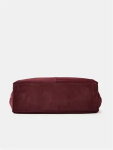 Close-up detail of the burgundy suede tote bag bottom, showing neat stitching and material.