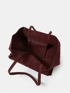 Burgundy suede tote bag interior detail, showing spacious compartment and zippered pocket.