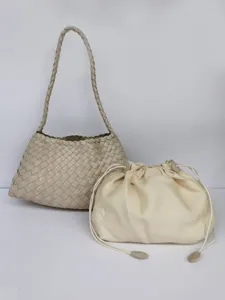 Dettaglio borsa a tracolla in pelle intrecciata, elegante borsa baguette beige sotto il braccio.
