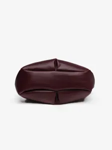 Gros plan très détaillé sur le fond plissé élégant du sac cabas en cuir marron foncé.