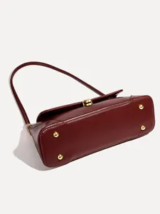 Detailed view of the retro burgundy shoulder bag showing bottom metal feet and clasp.