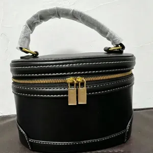 Elegante bolso cosmético negro de cuero con costuras blancas contrastadas y cremalleras doradas.