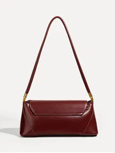 Detailed view of burgundy leather shoulder bag with gold hardware and geometric panels.