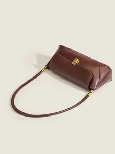 Vintage burgundy shoulder bag detail, elegant underarm design with chic gold clasp and slim strap.