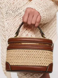 Bolso neceser elegante de lona y paja con ribete de cuero marrón y asa superior.
