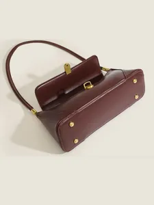 Vintage burgundy shoulder bag featuring metal lock closure and bottom studs, classic.