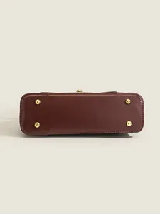 Detailed view of the structured leather shoulder bag bottom with protective metal feet.