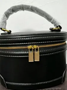 Bolso cosmetico estructurado negro caja de maquillaje con cremalleras doradas y costuras.