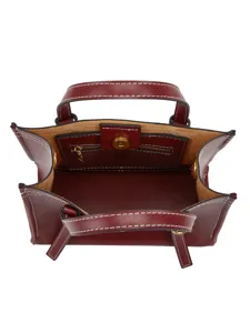 Vue de dessus détaillée d'un sac cabas en cuir rouge foncé avec coutures contrastées.