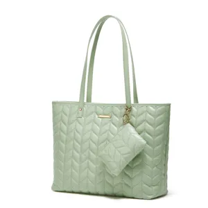 Gros plan du sac cabas matelassé vert clair montrant la texture et la pochette assortie.