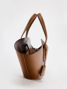 Vue détaillée du sac seau en cuir marron avec poignées et surpiqûres pour le quotidien.