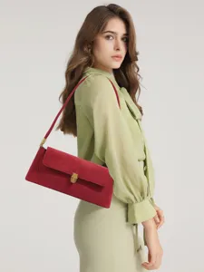 Red suede underarm shoulder bag worn detail view showing premium texture and metallic lock.