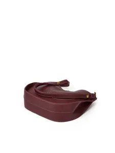 Détail du sac croissant en cuir bordeaux souple, mettant en valeur de fines surpiqûres blanches.