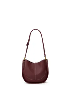 Détail de sac porté épaule en cuir bordeaux, élégantes surpiqûres et quincaillerie métallique.