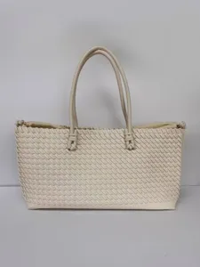 Detalle de bolso tote tejido en cuero artesanal, elegante bolso de hombro beige para trabajo.