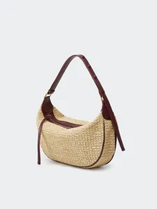 Detailed view of stylish straw hobo bag with brown leather trim and clear details.