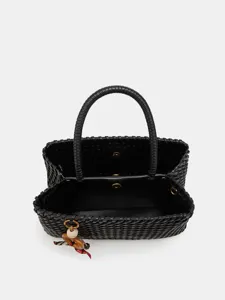 Detailed view of black woven leather handbag, highlighting texture and chic charm.