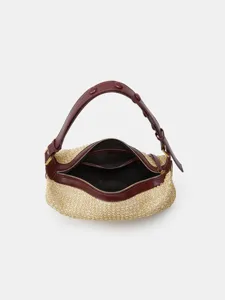 Detailed view of the straw woven crescent shoulder bag, featuring contrast leather trim and zipper.