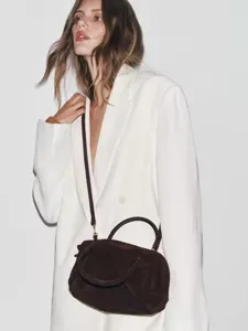 Sac bowling en daim marron foncé avec bandoulière associé à un blazer blanc détail de mode
