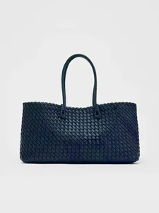 Vista detallada del elegante bolso tote de cuero tejido en azul oscuro con asas clásicas.