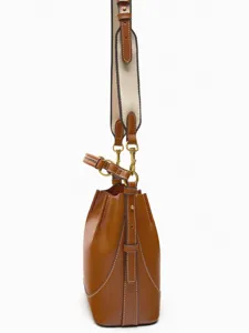 Braune Leder Beuteltasche Seitenansicht mit breitem Leinengurt und Metallbeschlägen.