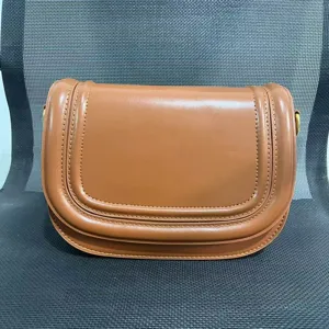 Brown leather saddle bag for women with flap closure, magnetic snap and contrast stitching design.