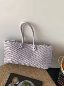 Vista detallada del bolso tote de cuero tejido en lavanda, diseño artesanal elegante.