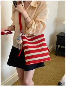 Red and white striped woven bucket bag with stylish shoulder strap and cute bear pendant.