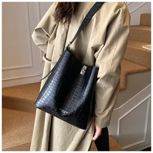 Vue détaillée et rapprochée de l'élégant sac cabas en cuir noir façon croco avec fermoir en métal.
