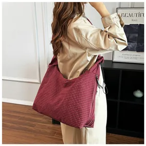 Dettaglio di una borsa a tracolla morbida a quadri rossi, ideale per un look casual autunnale.