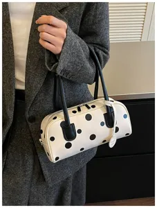 Nahaufnahme der weiß-schwarzen Pünktchen-Bowlingtasche aus Leder mit eleganten Doppelgriffen.