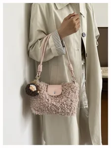 Detailed view of the plush shoulder bag worn by a model against a wall in autumn style.